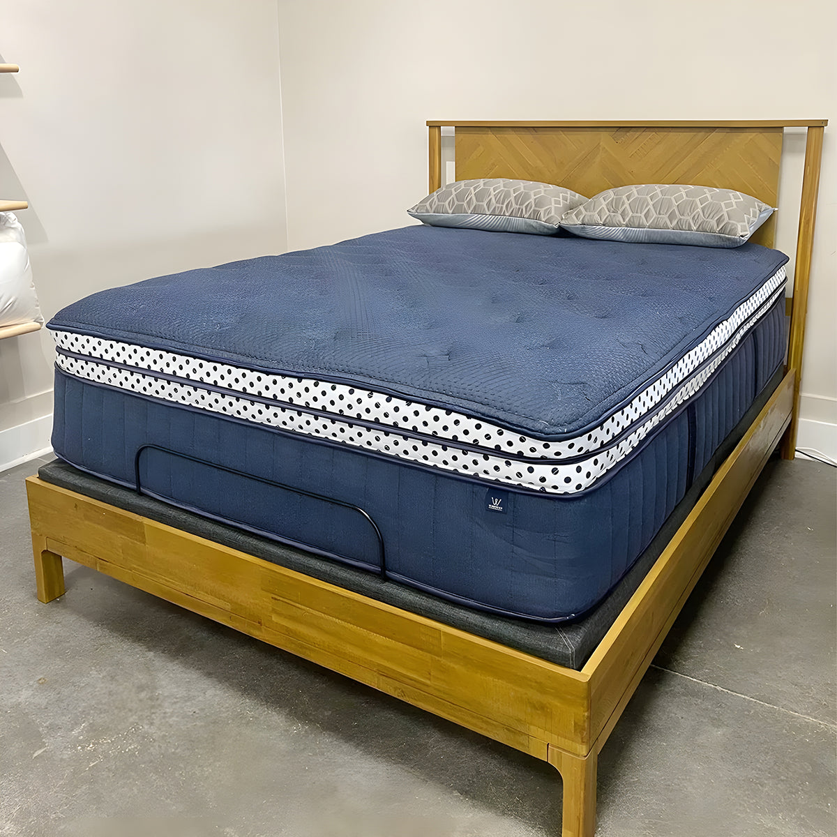 Angle view of the WinkBeds Blue 17" Mattress on an adjustable base showing thick wrapped coil support layers.