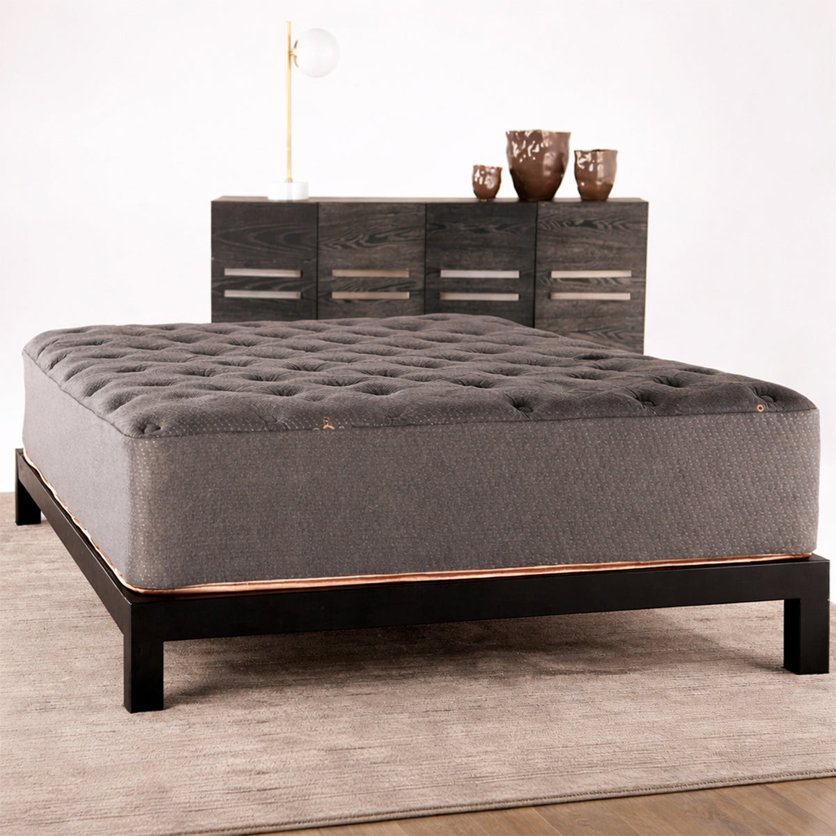 Front-facing view of a contemporary master bedroom with the Tommie Copper Core Znergy mattress and grey upholstered headboard.
