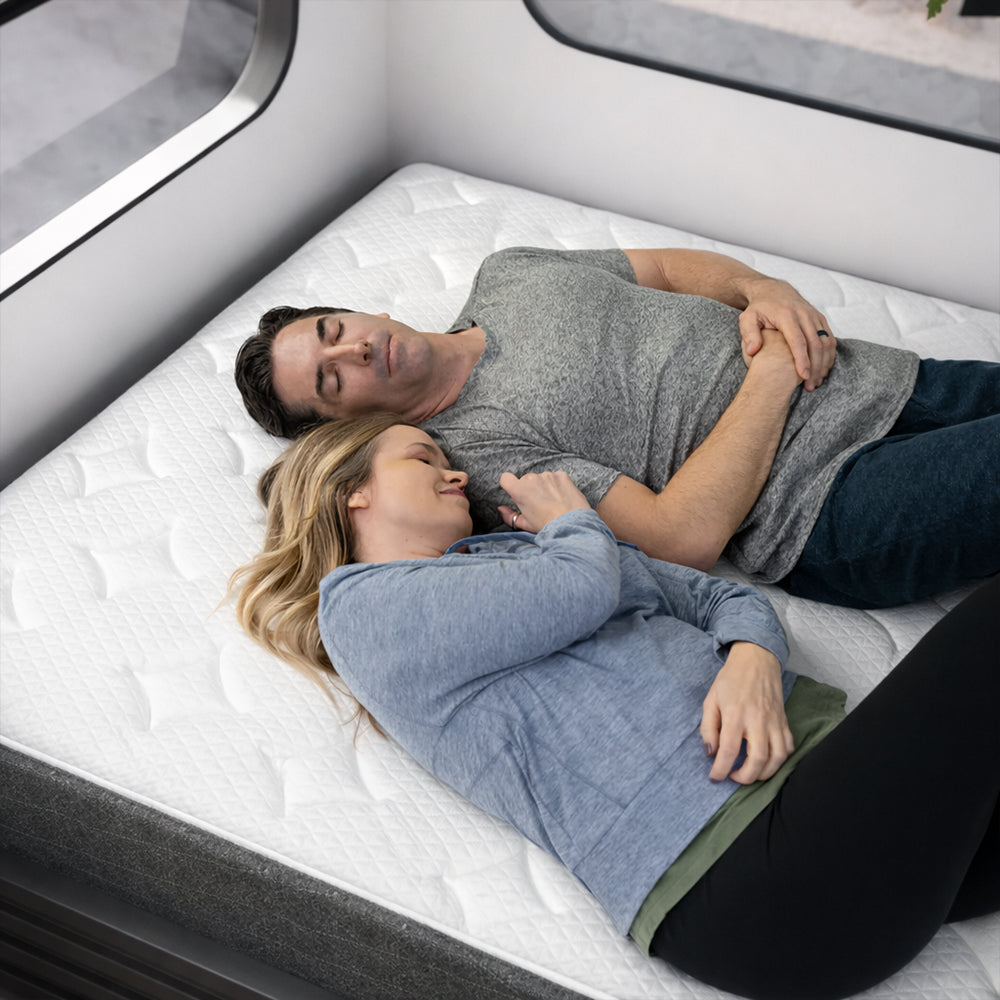 Couple sleeping soundly on a GhostBed RV hybrid mattress in a camper, highlighting motion isolation for travel sleep.
