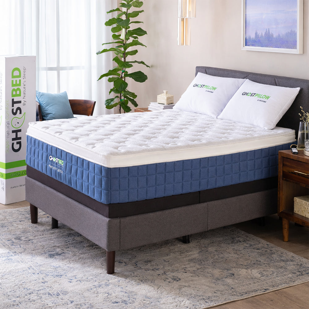 The GhostBed Performance 14-inch cooling hybrid mattress styled on a modern grey upholstered platform bed frame in a bright, contemporary master bedroom.
