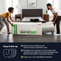 Two people unboxing a GhostBed mattress-in-a-box in a modern bedroom, demonstrating the easy setup and expansion of the hybrid bed.
