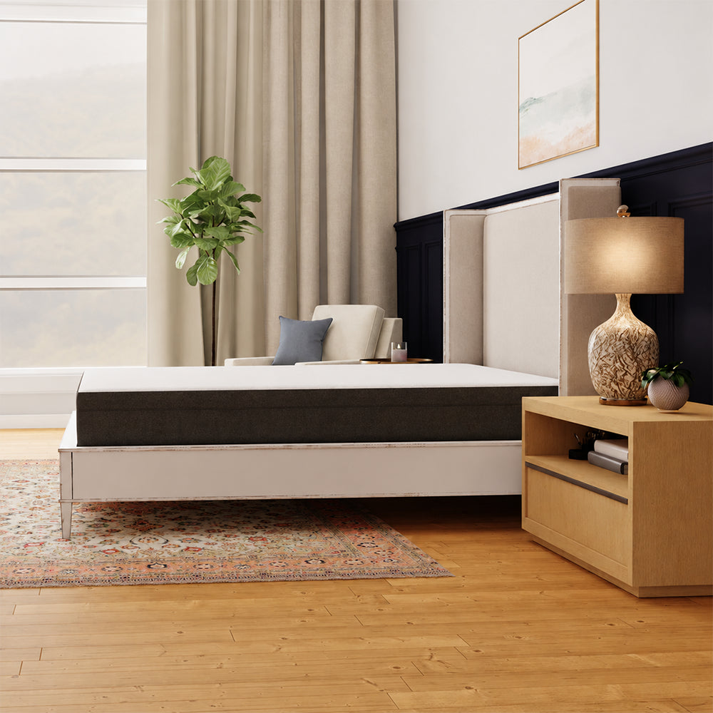 Side profile of the Rose 10-inch mattress by South Bay featured in a master bedroom interior with a white wingback headboard and hardwood floors.
