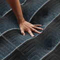 Hand pressing on Beautyrest World Class plush mattress to show responsive contouring and pressure relief.
