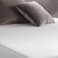 Close-up of soft jersey fabric on the Weekender by Malouf mattress protector for a noiseless sleep surface.
