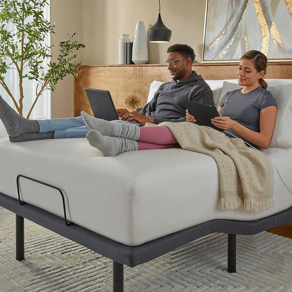 Lifestyle view of a couple sitting on the Baselogic Gold adjustable base using the split-head functionality for individual comfort preferences.
