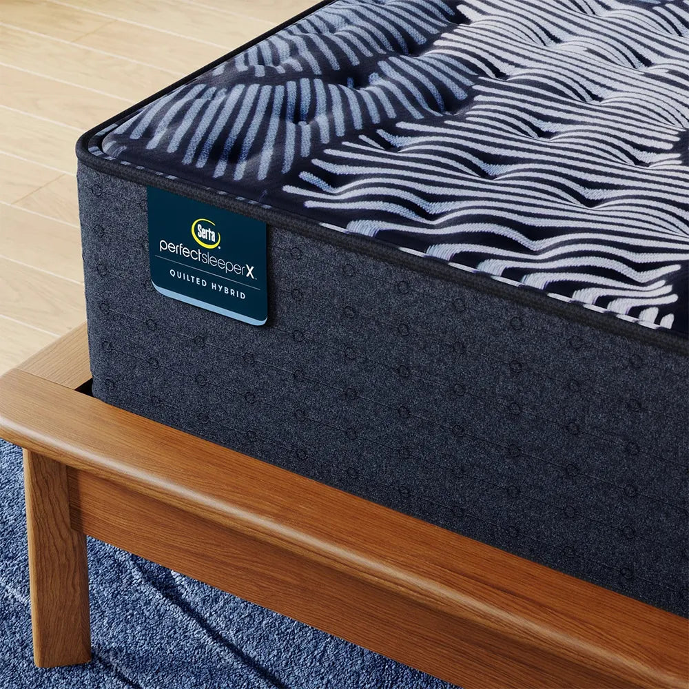Close-up of Serta Perfect Sleeper X Max branding and quilted surface on a premium wooden bed frame.
