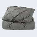 Folded charcoal grey SleepTone Tranquility pinch pleat comforter and sham set on a white background.

