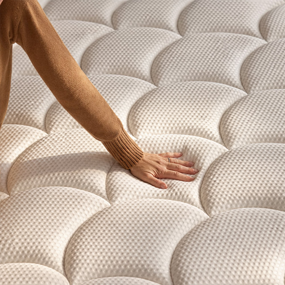 Close-up of a hand pressing into the DreamCloud Classic hybrid mattress surface to demonstrate responsive foam contouring and pressure relief.