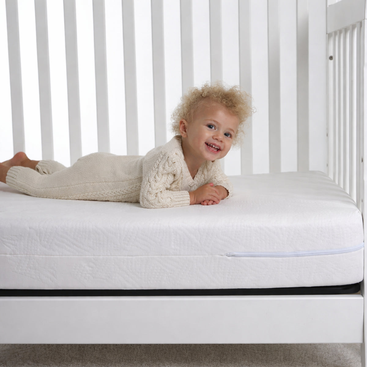 Happy toddler in nursery setting resting on the firm 2-Stage Classic Crib & Toddler Mattress.