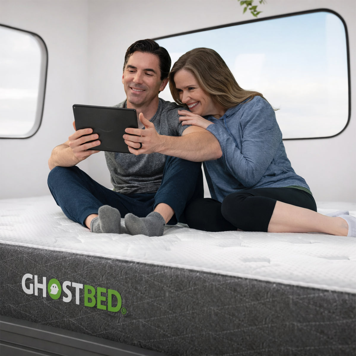 Couple relaxing on a supportive GhostBed RV hybrid mattress in a van, demonstrating the bed's stable surface.
