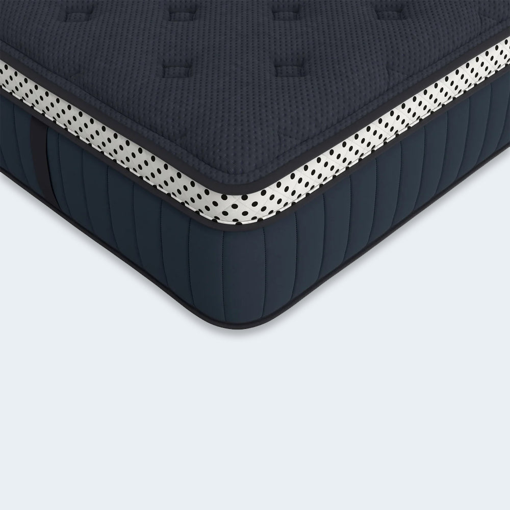 Detailed close-up of the WinkBeds Blue mattress corner showcasing the white polka-dot reinforced tape edge and breathable navy quilted fabric.
