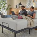Couple using a laptop and tablet in bed facilitated by the baselogic™ Pearl Adjustable Base head-tilt feature for ergonomic back support.
