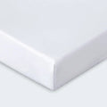 Corner of a white Dri-Tec fitted crib sheet with a secure elastic band for infant safety.
