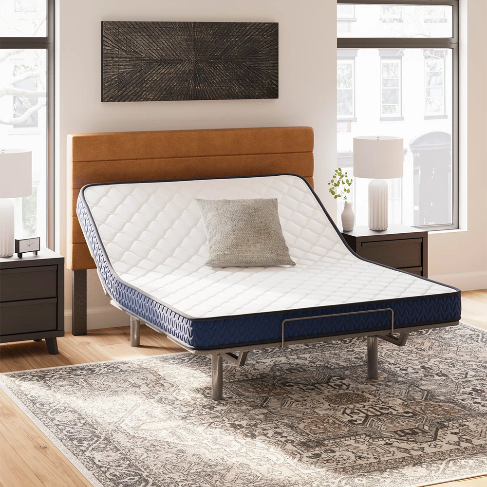 Ashley Firm 6-inch Mattress on a raised adjustable power base in a designer bedroom, demonstrating flexibility and ergonomic support.
