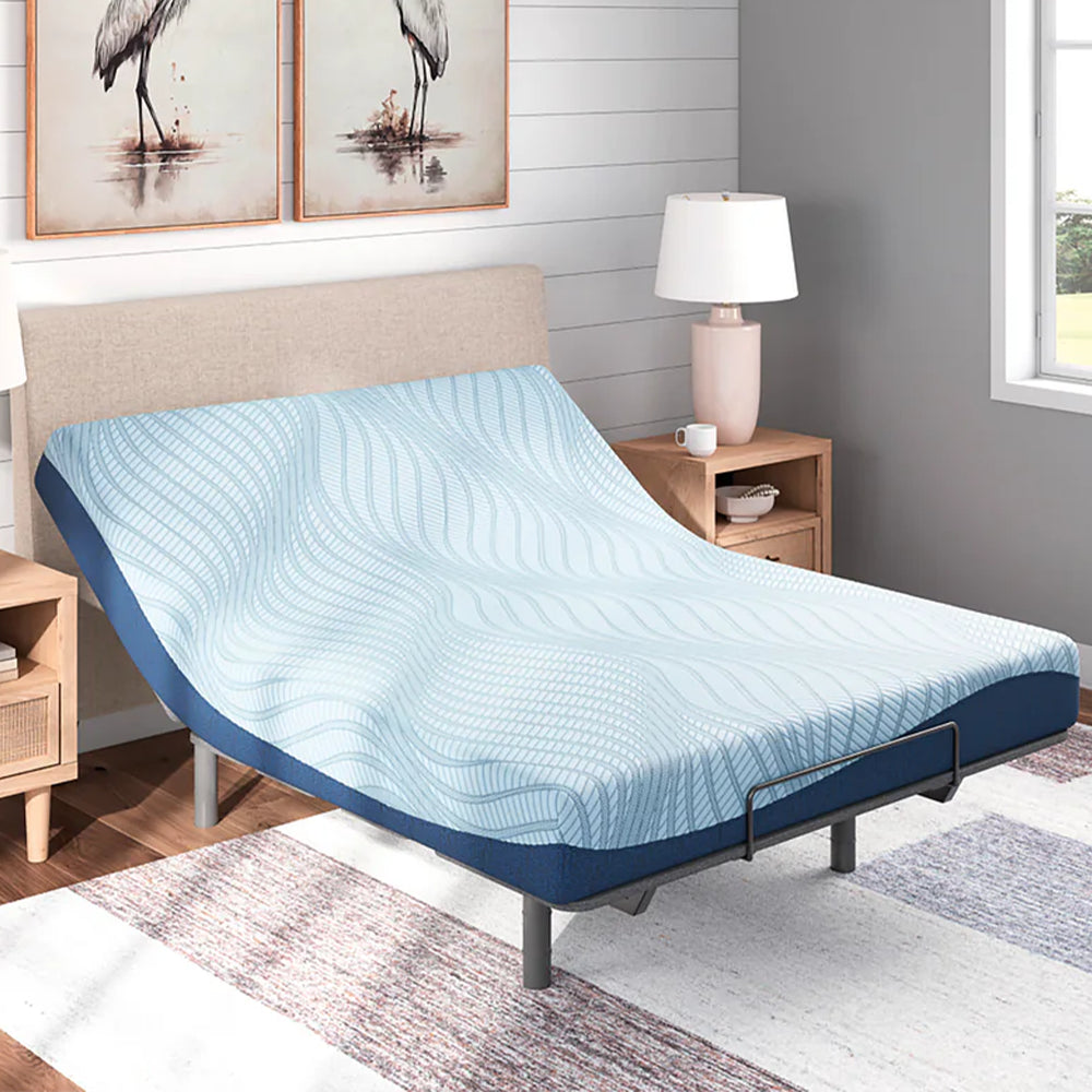 Ashley Peak 2.0 memory foam mattress with the head section elevated on an adjustable power base in a bright coastal-style bedroom.
