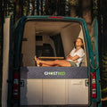 Woman lounging on a GhostBed RV 10-inch hybrid mattress inside a camper van, showcasing van life comfort and style.
