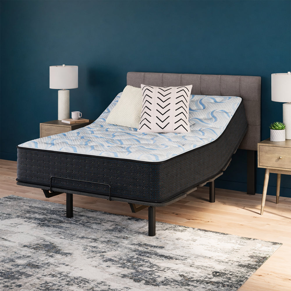 Ergonomic bedroom setup with the Elite Springs 14-inch firm mattress by Ashley elevated on an adjustable base for personalized comfort.
