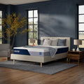 Angled lifestyle shot of the Nectar Classic Firm 12-inch mattress on a contemporary grey upholstered bed frame in a designer master bedroom.
