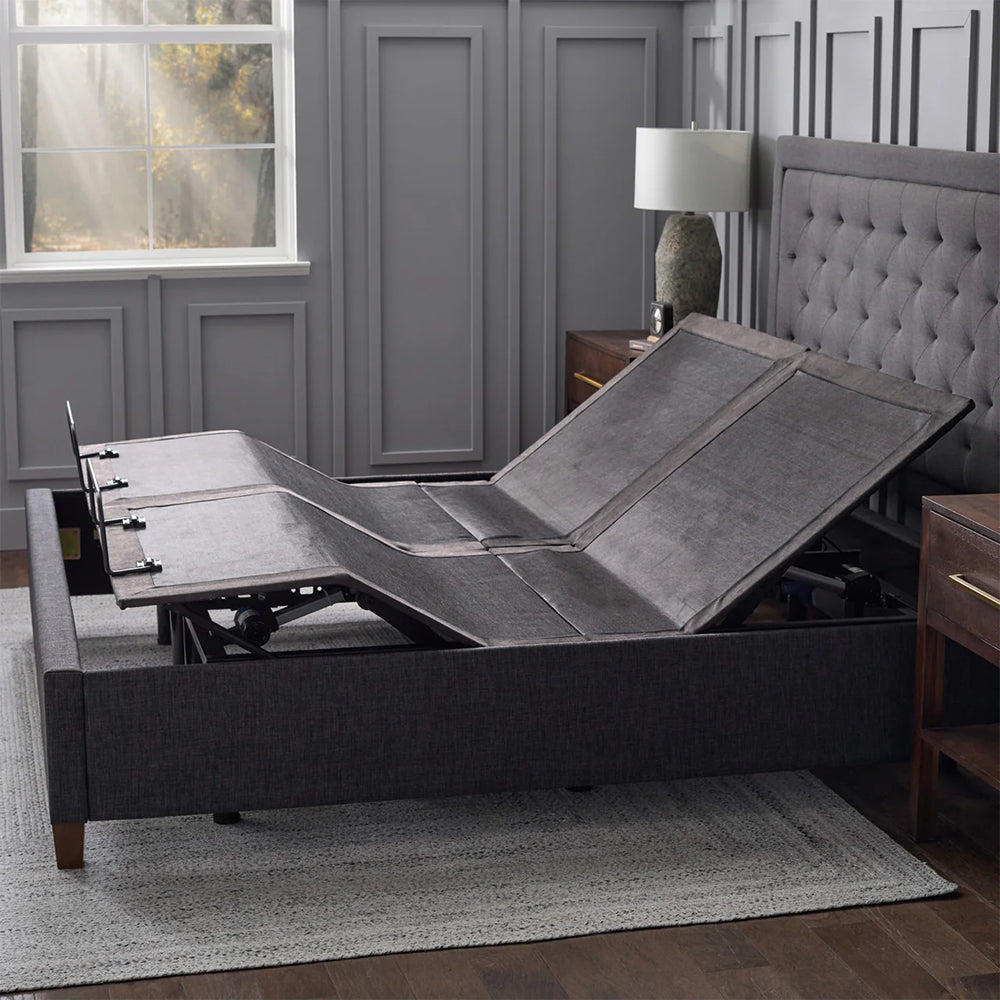 Malouf E455 adjustable base articulated within a charcoal fluted upholstered bed frame in a contemporary room.
