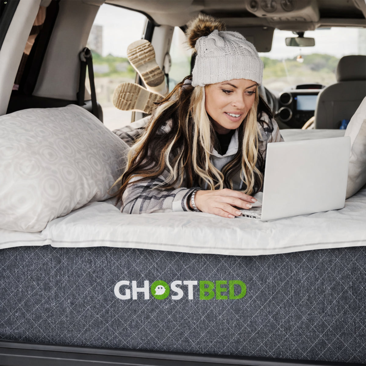 Using a laptop on the supportive RV 10" Foam Mattress in a van bedroom setting for maximum travel comfort.