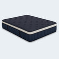 Three-quarter angled view of the navy blue WinkBeds Blue 15-inch luxury firm mattress featuring a tufted top and signature polka-dot border.
