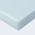 Close-up corner of a light blue Hyper-Wool fitted crib sheet for a soft, moisture-wicking sleep surface.
