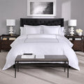 Modern bedroom featuring white SleepTone Hotel Luxury sheets with silver double-stripe embroidery.
