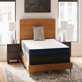Firm 6-inch Mattress by Ashley styled on a tan upholstered platform bed in a modern urban master bedroom setting.
