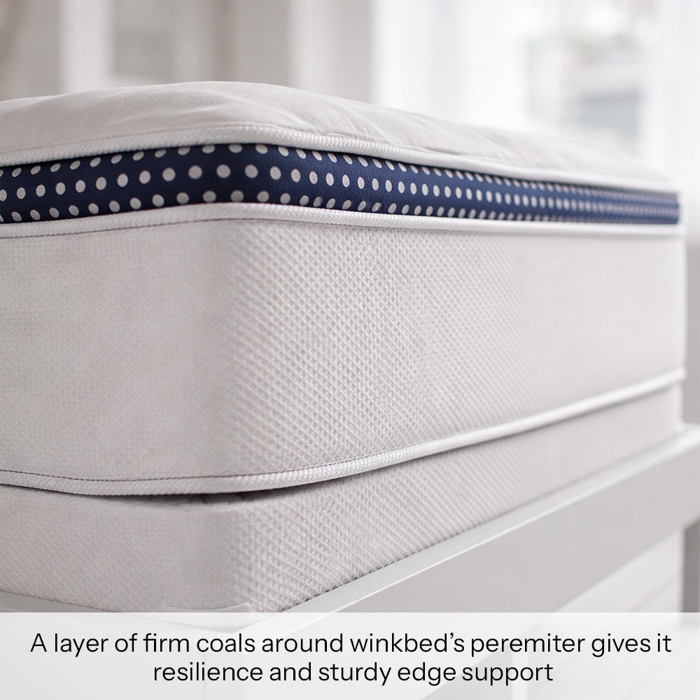 Side profile view of the WinkBed hybrid mattress highlighting the reinforced perimeter and signature navy blue polka-dot ribbon trim.
