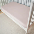 Soft pink Hyper-Wool performance crib sheet on a white crib for a cozy, moisture-wicking nursery.