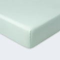 Close-up corner of a sage green Hyper-Wool fitted crib sheet for a secure and breathable mattress fit.
